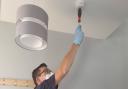 A member of Essex County Fire and Rescue Service's Home Fire Safety team testing a smoke alarm