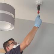 A member of Essex County Fire and Rescue Service's Home Fire Safety team testing a smoke alarm